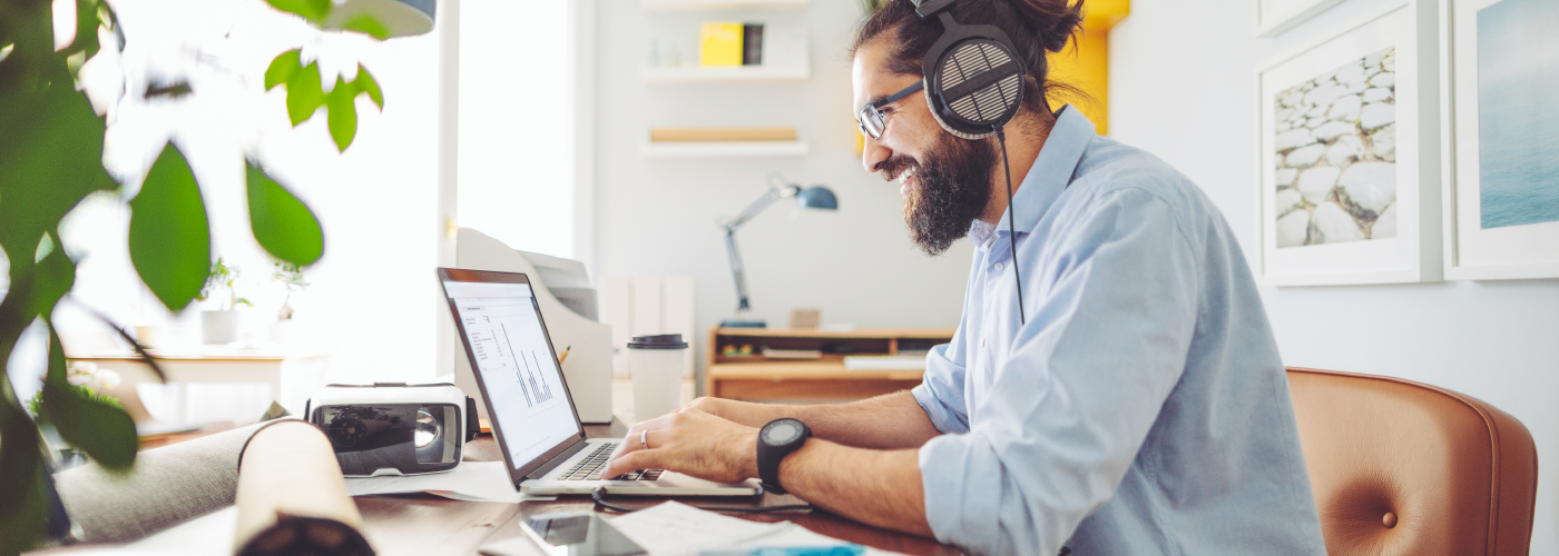 Bearded man with headphones working from home on laptop