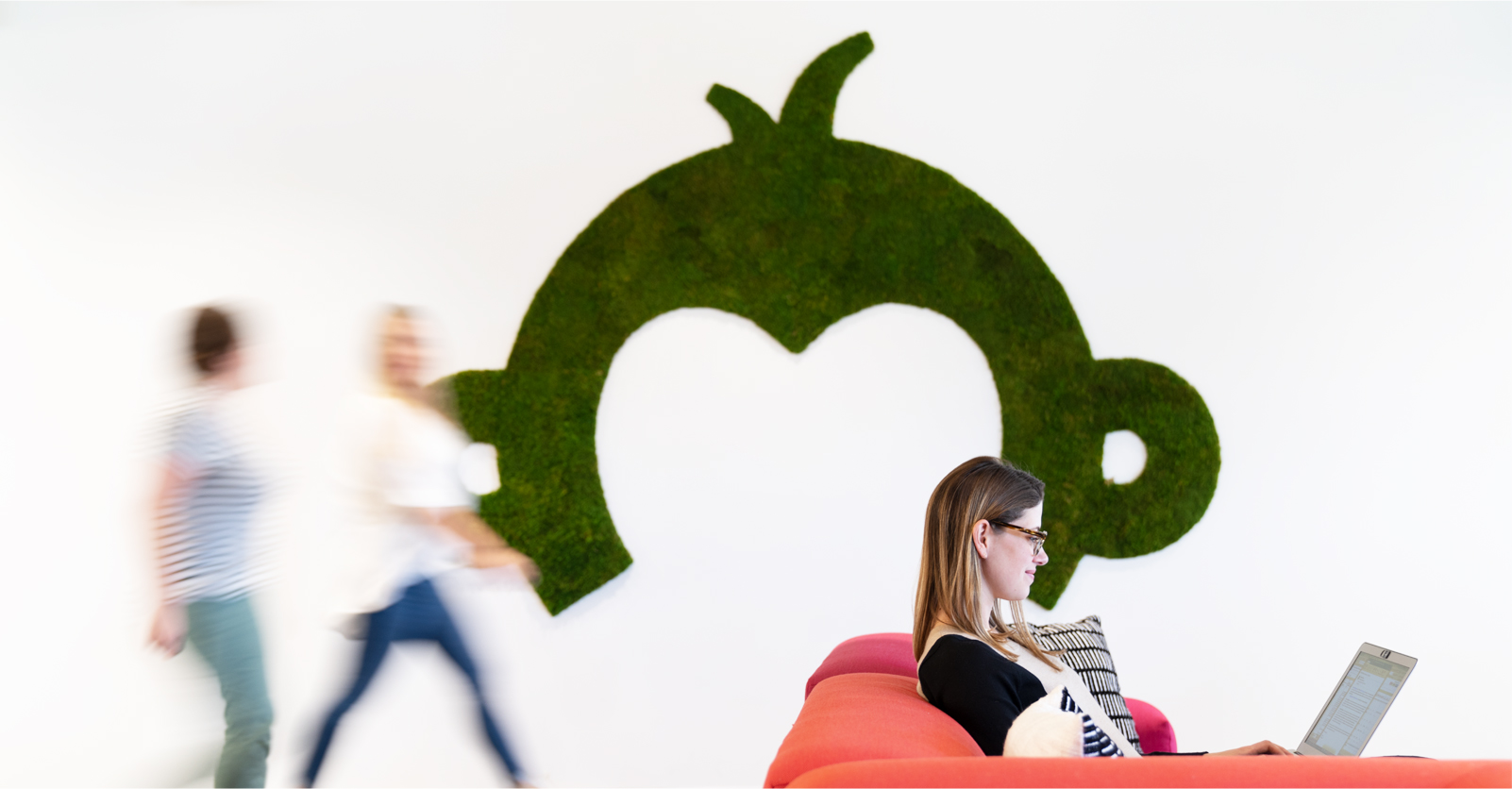 Surveymonkey logo on wall with motion blurred people walking by