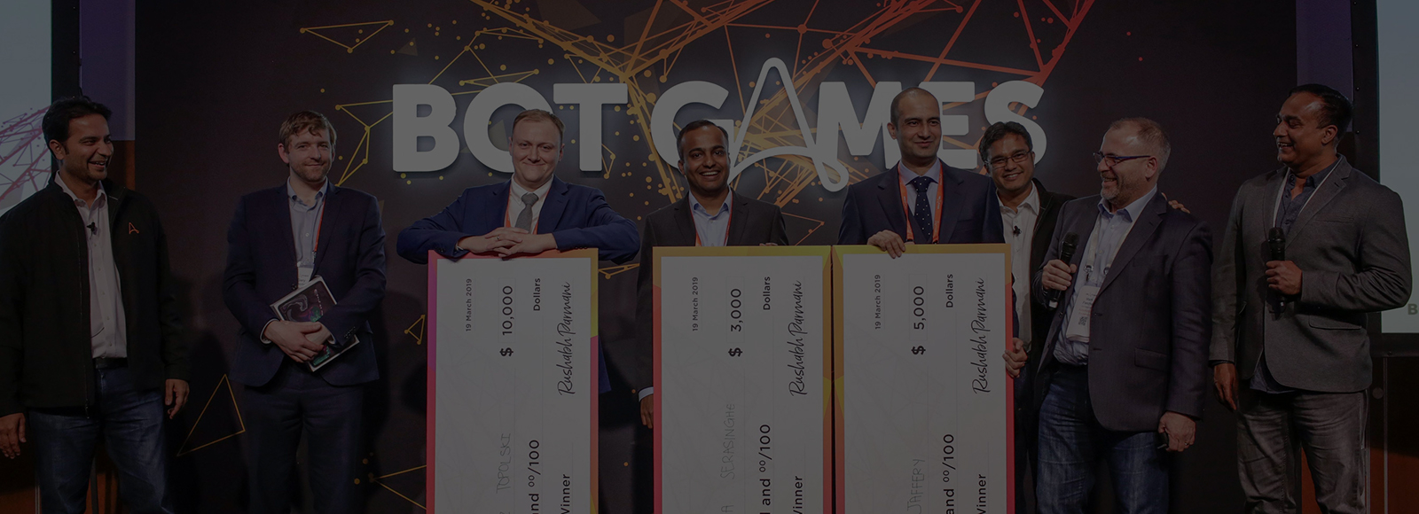 Botgames event with 3 contestants posing with giant checks