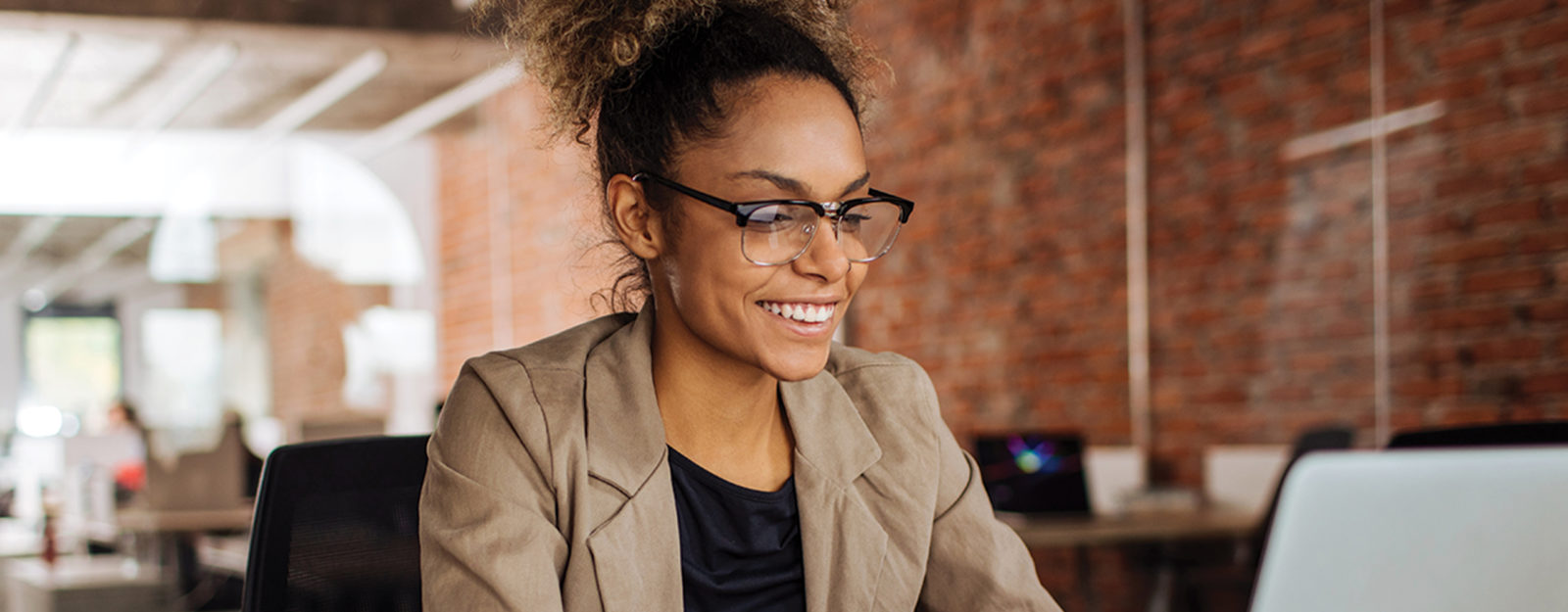 Woman with glasses in office working on laptop