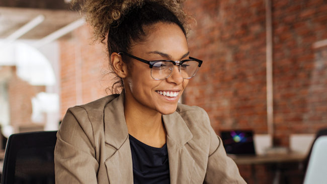 Woman with glasses in office working on laptop