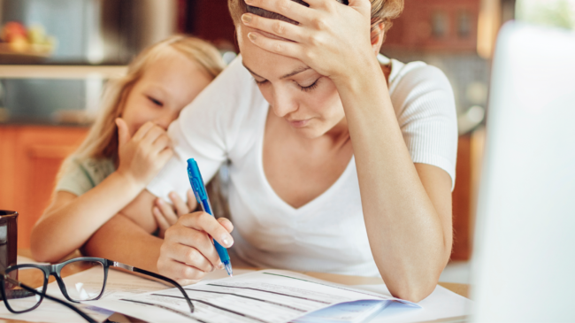 Overworked mom signing forms with kid