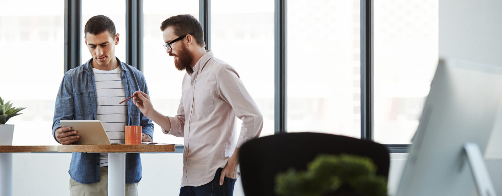 DIM blog - How to be a better teammate: Two office workers talking together at a table