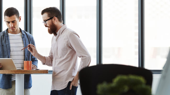 DIM blog - How to be a better teammate: Two office workers talking together at a table
