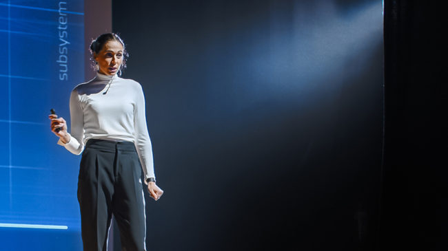 DIM blog - 7 tips for designing impactful keynotes: Woman on stage giving a presentation